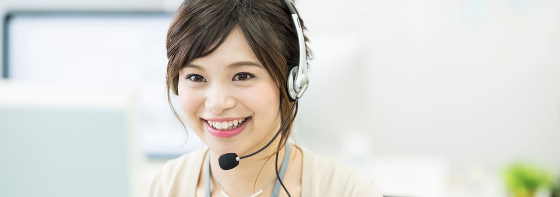 Frau mit Headset lacht vor ihrem PC